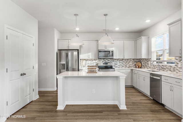 kitchen featuring stainless steel appliances, dark wood finished floors, a sink, and a kitchen island