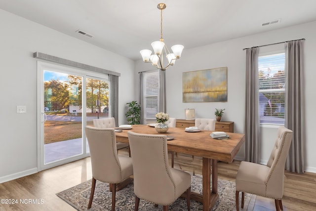 dining room with light wood-style floors, visible vents, and an inviting chandelier