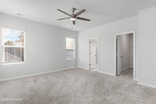 unfurnished bedroom featuring carpet floors, visible vents, a spacious closet, and baseboards