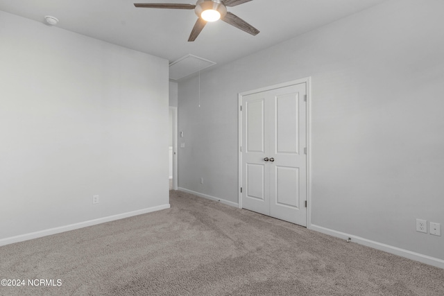 unfurnished bedroom featuring a ceiling fan, carpet flooring, attic access, and baseboards