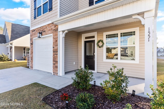 property entrance featuring concrete driveway, stone siding, a porch, and an attached garage