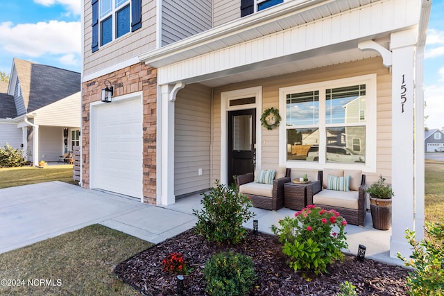 doorway to property with an attached garage, covered porch, stone siding, and concrete driveway