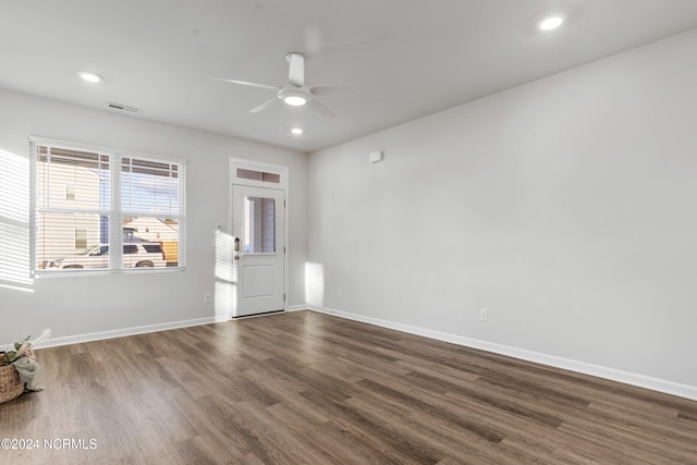 empty room with dark wood-style flooring, visible vents, and baseboards