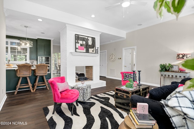 living room featuring crown molding, a brick fireplace, dark hardwood / wood-style floors, and ceiling fan