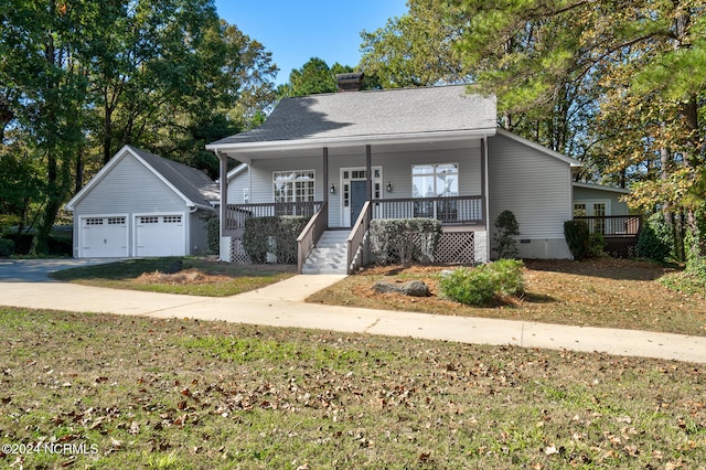 view of front facade with an outbuilding, covered porch, and a garage