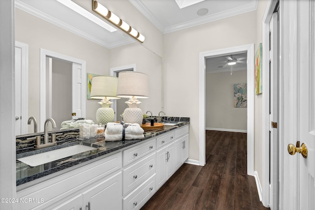 bathroom with a skylight, hardwood / wood-style floors, ceiling fan, vanity, and crown molding