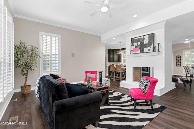 living room with ceiling fan, ornamental molding, dark hardwood / wood-style flooring, and a brick fireplace