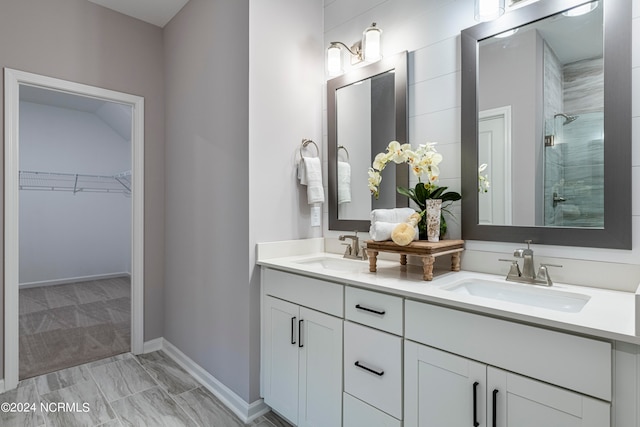 bathroom featuring tile flooring, vanity with extensive cabinet space, a shower, and dual sinks