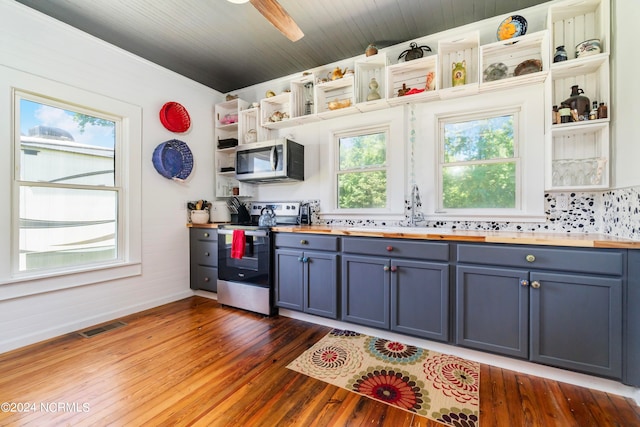 kitchen featuring tasteful backsplash, wood-type flooring, blue cabinets, sink, and appliances with stainless steel finishes