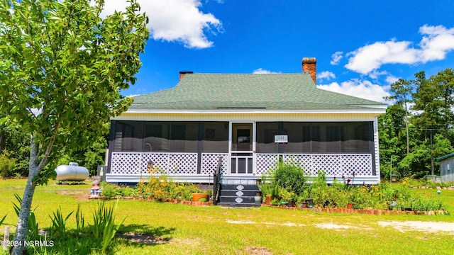 rear view of house featuring a sunroom and a yard