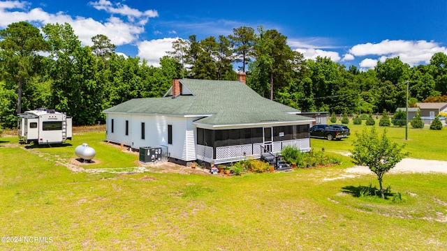 view of front of property featuring a front yard, a sunroom, and central AC