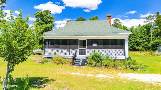 rear view of property with a sunroom and a lawn