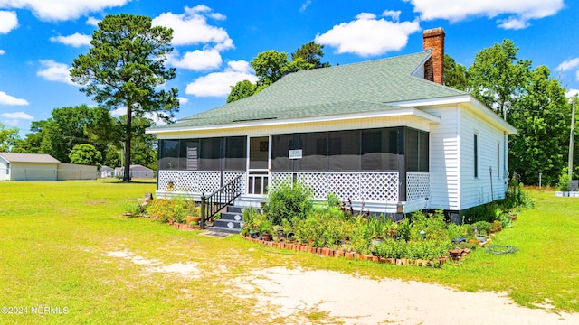 rear view of house featuring a sunroom and a yard