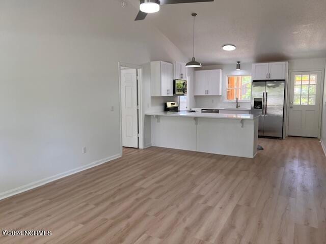 kitchen with light hardwood / wood-style floors, appliances with stainless steel finishes, white cabinets, decorative light fixtures, and ceiling fan