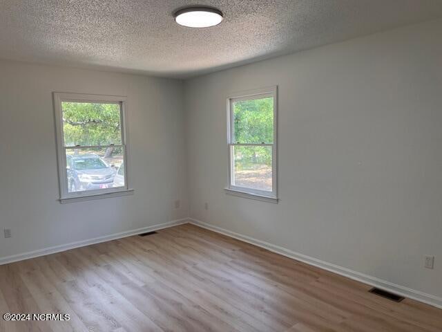 unfurnished room featuring a healthy amount of sunlight, a textured ceiling, and wood-type flooring