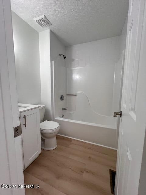 full bathroom featuring shower / bathing tub combination, wood-type flooring, a textured ceiling, toilet, and vanity