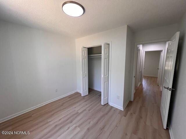 unfurnished bedroom with a closet, light hardwood / wood-style floors, and a textured ceiling