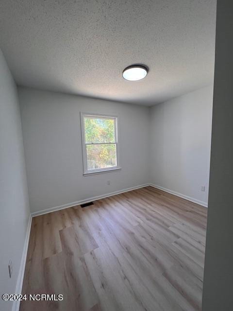 spare room featuring a textured ceiling and wood-type flooring