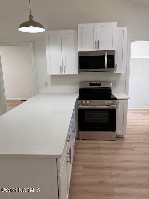 kitchen featuring stainless steel appliances, white cabinets, light hardwood / wood-style floors, and decorative light fixtures