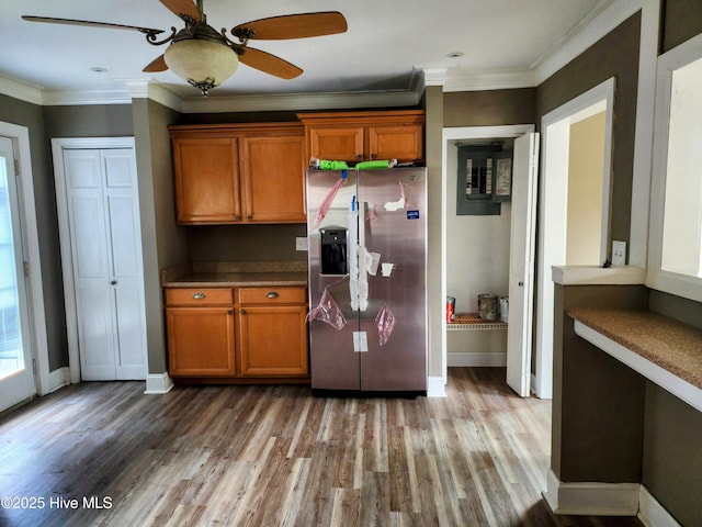 kitchen with brown cabinets, light wood-style floors, stainless steel fridge with ice dispenser, crown molding, and baseboards