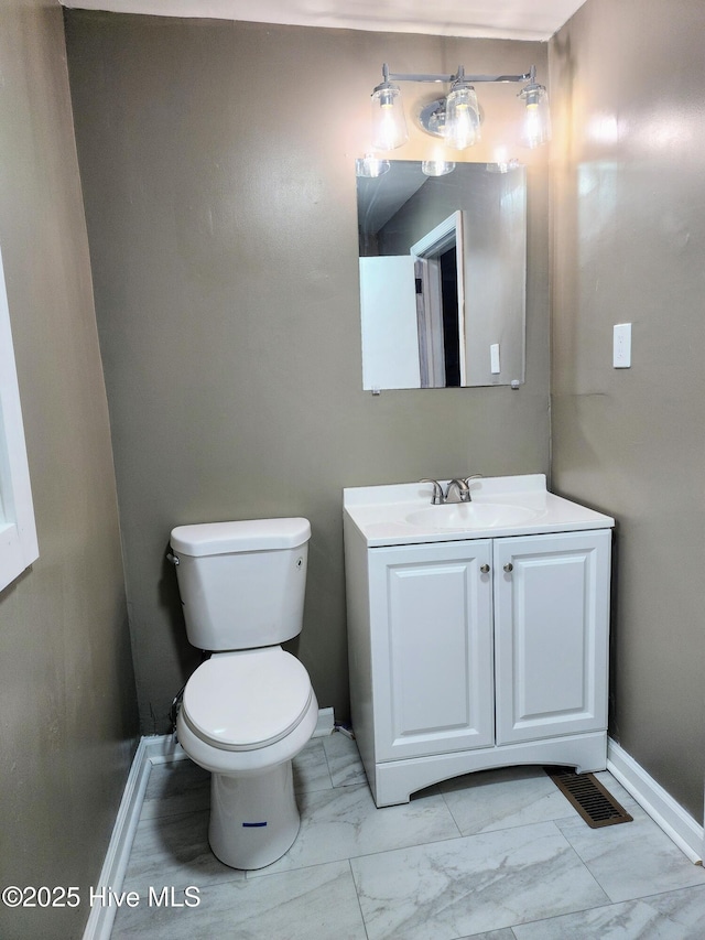 half bathroom with vanity, visible vents, baseboards, toilet, and marble finish floor