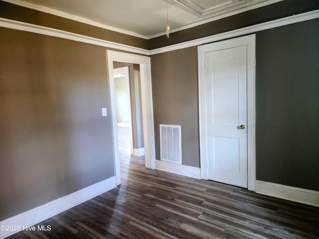 unfurnished bedroom featuring crown molding, dark wood-style floors, baseboards, and visible vents