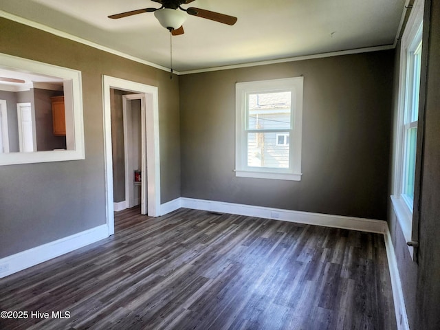 spare room featuring dark wood-style floors, a ceiling fan, baseboards, and ornamental molding