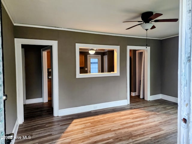 spare room with crown molding, wood finished floors, baseboards, and ceiling fan