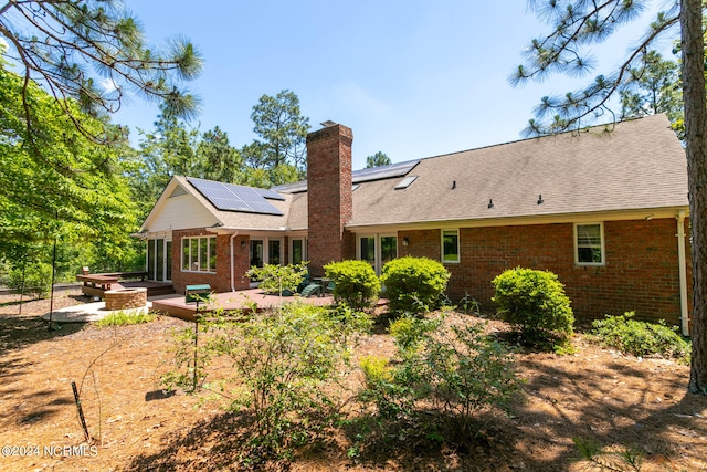 back of property featuring a deck and solar panels