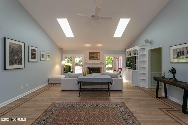 living room with high vaulted ceiling, wood-type flooring, ceiling fan, and a skylight