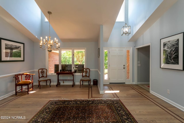 foyer entrance with a notable chandelier, hardwood / wood-style floors, and a towering ceiling