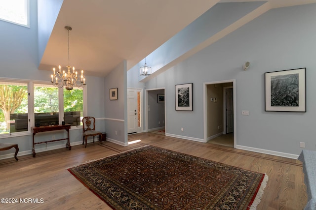 foyer entrance with high vaulted ceiling, hardwood / wood-style floors, and a notable chandelier