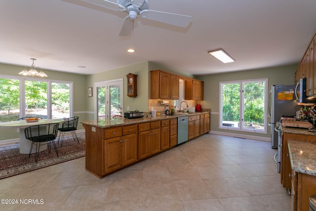 kitchen featuring dishwasher, ceiling fan with notable chandelier, light tile floors, hanging light fixtures, and sink