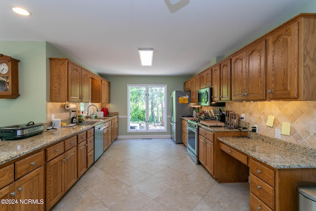 kitchen with appliances with stainless steel finishes, sink, light tile flooring, and tasteful backsplash