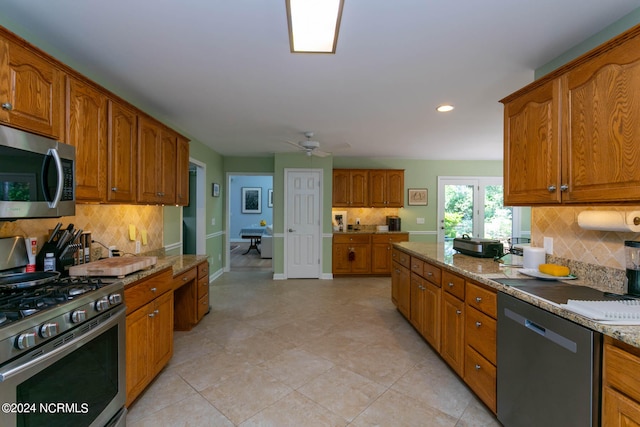 kitchen with appliances with stainless steel finishes, ceiling fan, tasteful backsplash, and light tile flooring