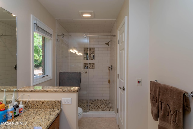 bathroom with tile flooring, tiled shower, toilet, and large vanity