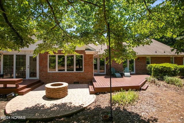 rear view of house featuring a deck, a patio area, and an outdoor fire pit