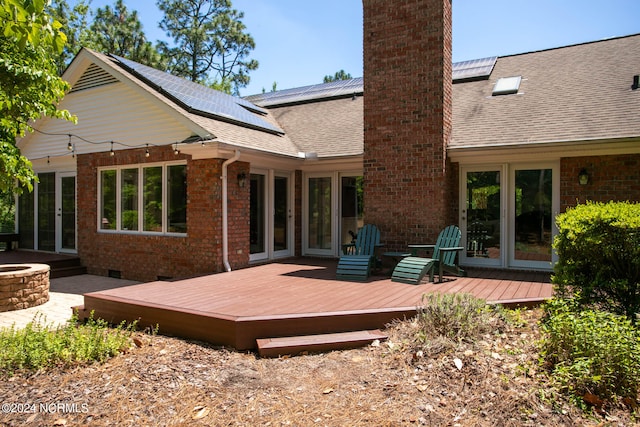 rear view of property with french doors, a deck, and solar panels