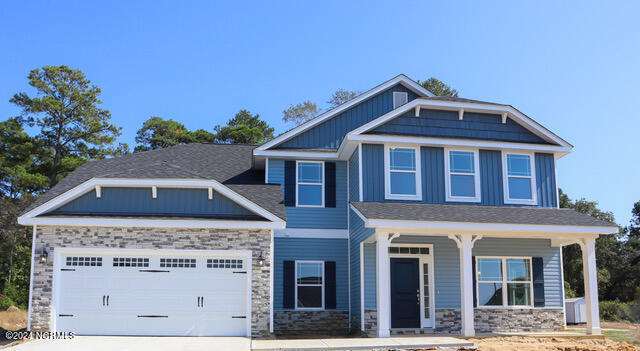 craftsman inspired home featuring a porch, a front yard, and a garage