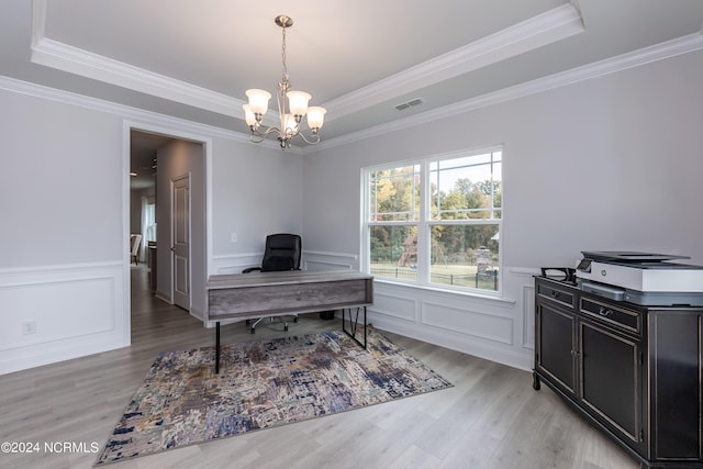 unfurnished dining area with wood-type flooring, a tray ceiling, ornamental molding, and a notable chandelier