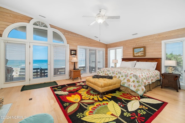 bedroom with lofted ceiling, wooden walls, ceiling fan, access to exterior, and light hardwood / wood-style floors