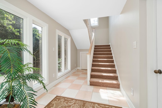 staircase with tile patterned flooring and lofted ceiling