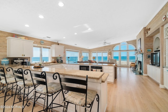 kitchen with ceiling fan, a water view, kitchen peninsula, and a breakfast bar