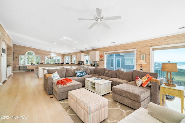 living room featuring wooden walls, ceiling fan, light hardwood / wood-style floors, and lofted ceiling