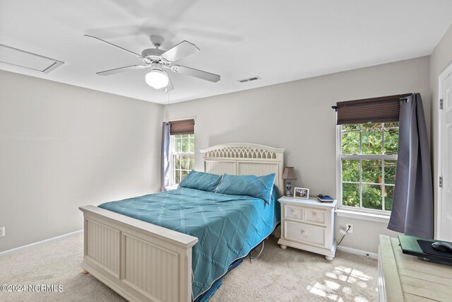 bedroom featuring ensuite bath, multiple windows, light wood-type flooring, and ceiling fan