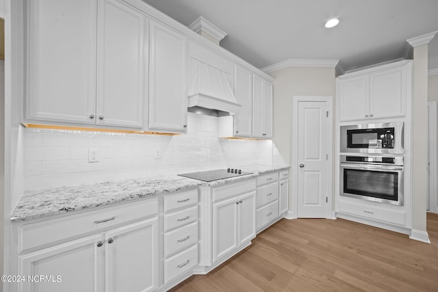 kitchen with appliances with stainless steel finishes, light wood finished floors, white cabinets, tasteful backsplash, and ornamental molding