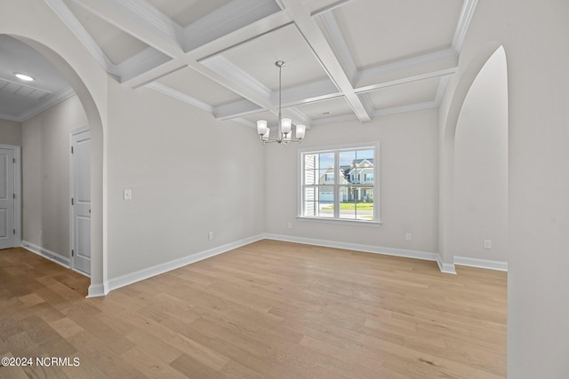 empty room featuring arched walkways, light wood-type flooring, beamed ceiling, coffered ceiling, and a chandelier