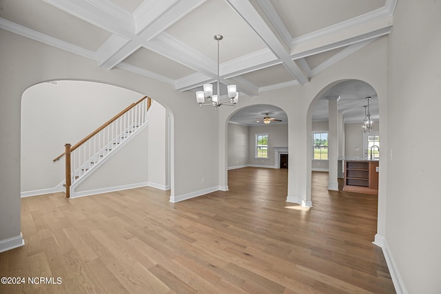 unfurnished living room with coffered ceiling, light wood finished floors, a chandelier, beam ceiling, and arched walkways