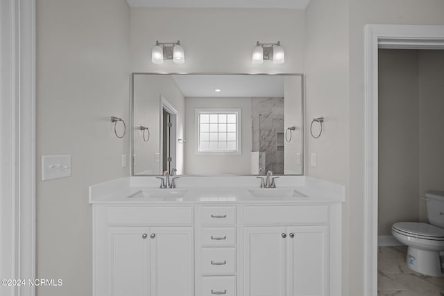 full bathroom featuring toilet, double vanity, marble look tiles, a marble finish shower, and baseboards