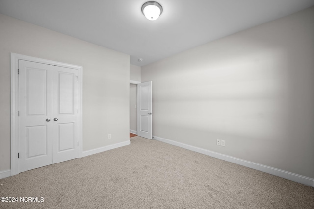 unfurnished bedroom featuring carpet floors, baseboards, and a closet